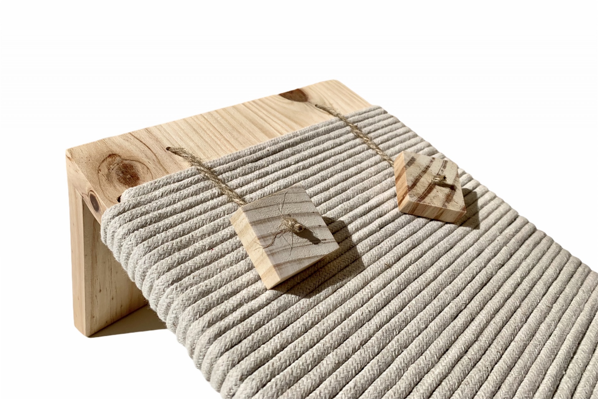Peça de mobiliário em madeira clara com almofadado cinzento texturizado e duas peças de madeira penduradas por cordas