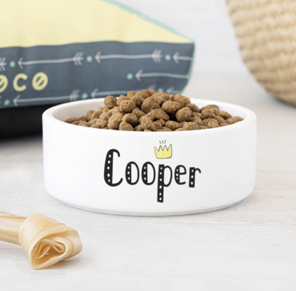 Tigela branca de cerâmica com texto 'Cooper' e ração para cão