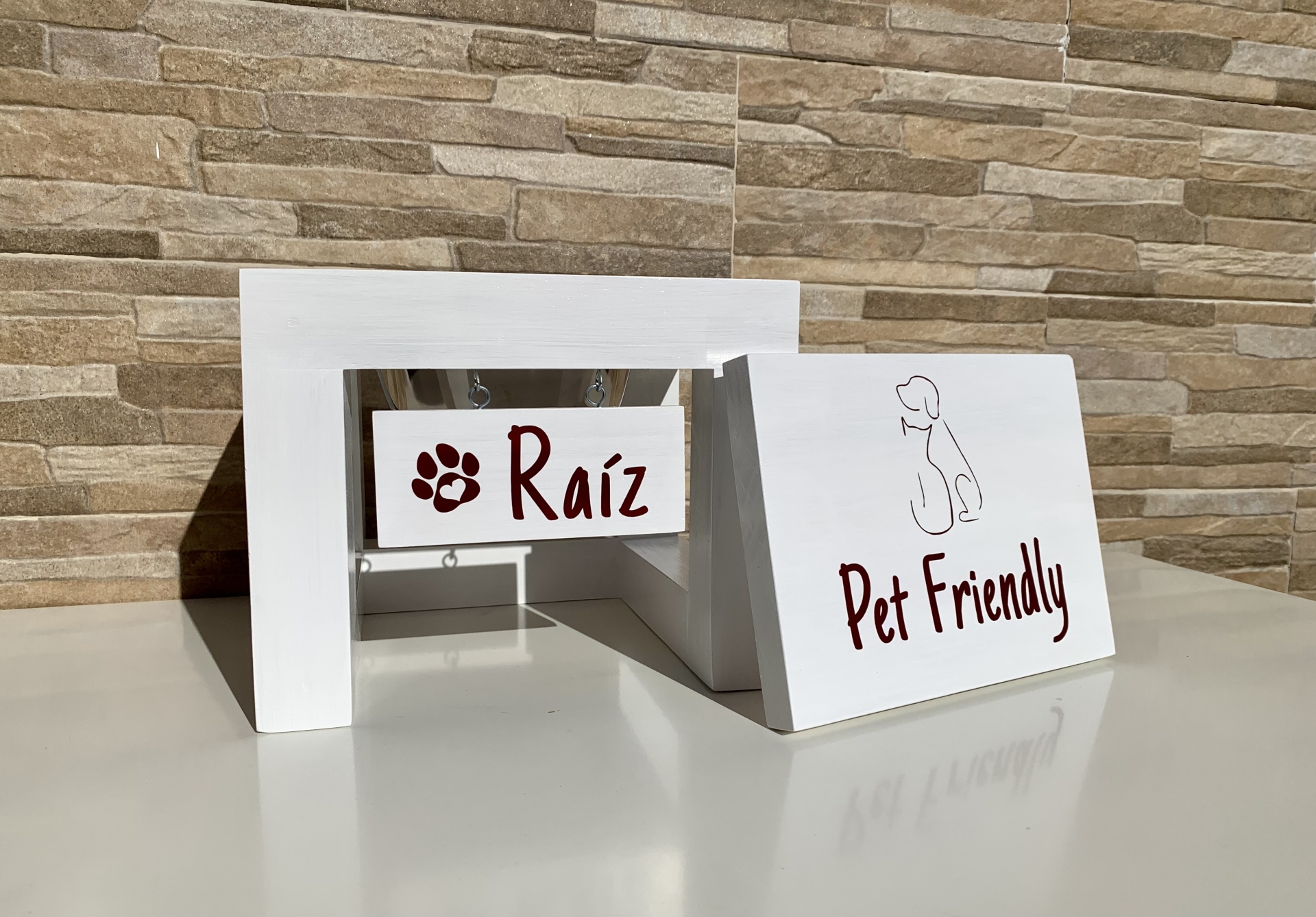 Estrutura branca de madeira com placas 'Raíz' e 'Pet Friendly' e desenho de cão.