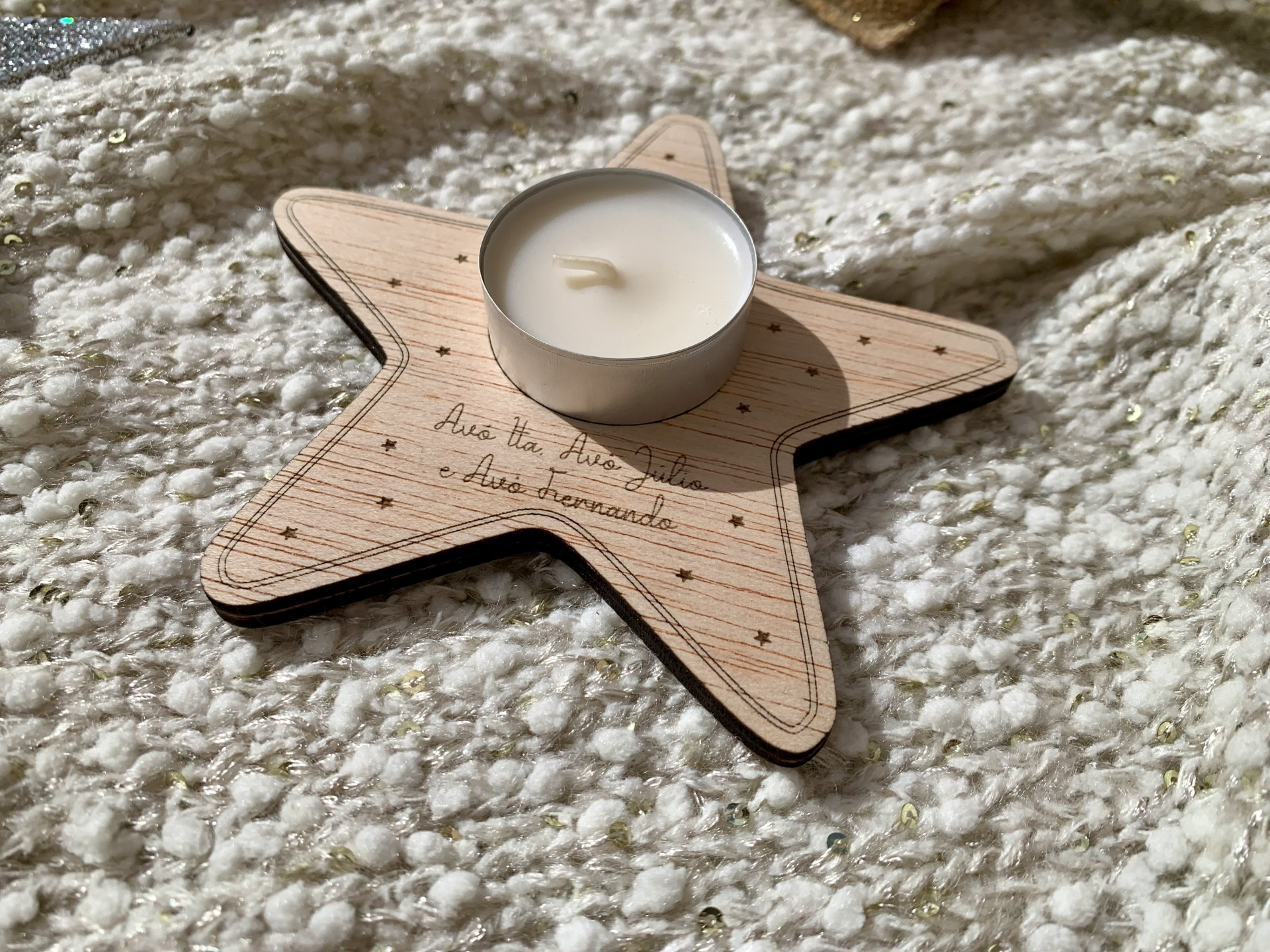 Vela branca numa base em madeira em forma de estrela com texto gravado