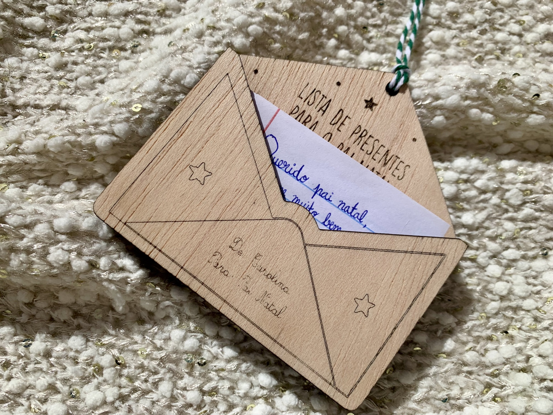 Etiqueta decorativa em forma de envelope e cartão pendurado em tecido cru com brilhos dourados