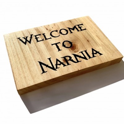 Placa de madeira clara com texto gravado 'WELCOME TO NARNIA'