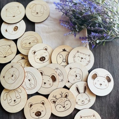 Peças redondas de madeira com desenhos de animais e saco de pano ao lado