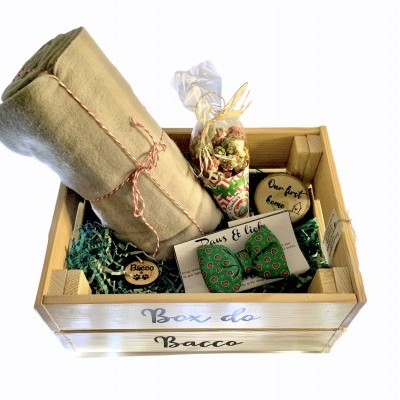 Caixa de madeira com itens de presente incluindo pano beige, caixa branca com laço verde, sementes e cartões de madeira