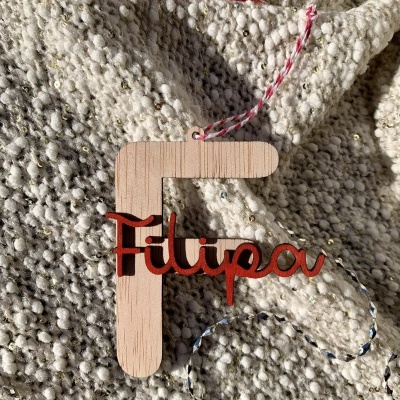 Ornamento de madeira com nome Filipa sobre tecido cinza texturizado