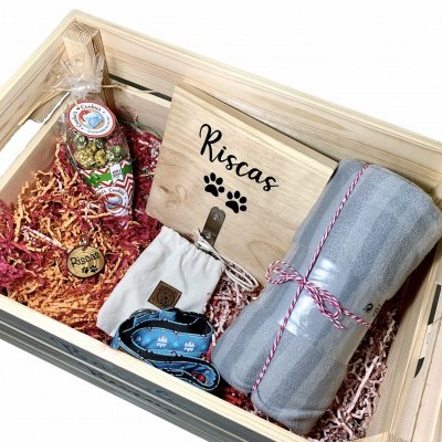 Caixa de presente madeira com linguiça, tábua de madeira, rolo de tecido cinza e sacos de tecido em papel colorido