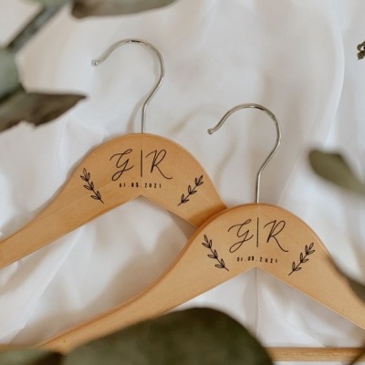 Cabides de madeira personalizados com texto e desenhos de folhagem sobre fundo branco