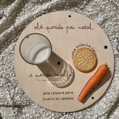 Prato redondo de madeira com leite, bolacha e cenoura sobre tapete cinza