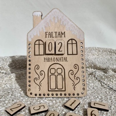 Calendário de contagem decrescente de Natal em madeira com forma de casa decorada, texto 'FALTAM 02 PARA O NATAL'.