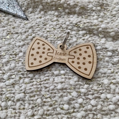 Pendente de madeira em forma de laço com padrão de pontos e texto gravado