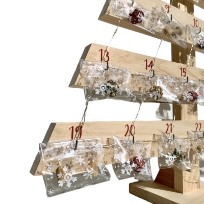 Árvore de madeira com saquinhos plásticos numerados decorados com flocos de neve, calendário do advento
