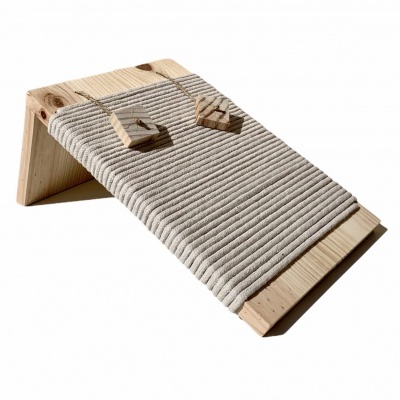 Banco inclinado em madeira clara com corda cinzenta enrolada e pequenos objetos triangulares de madeira