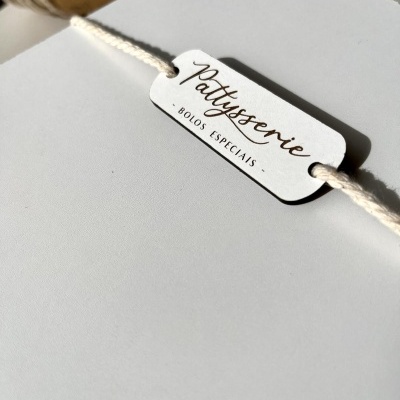 Etiqueta branca com cordão com texto Pattyssserie - BOLOS ESPECIAIS - sobre fundo branco