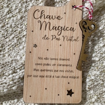 Placa de madeira com chave metálica pendurada e texto gravado que menciona chave mágica do Pai Natal