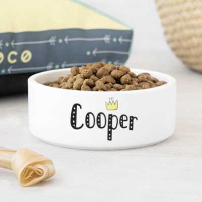 Tigela branca de cerâmica com texto 'Cooper' e ração para cão