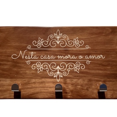 Tabuleiro de madeira castanha com texto branco e três ganchos metálicos