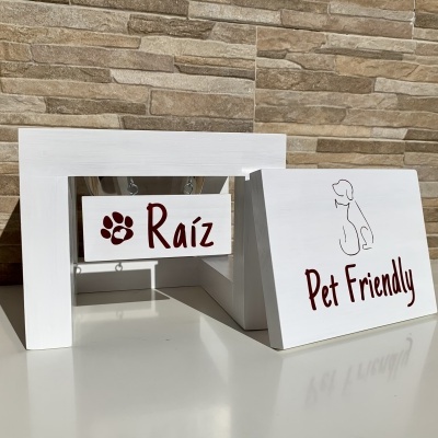 Estrutura branca de madeira com placas 'Raíz' e 'Pet Friendly' e desenho de cão.