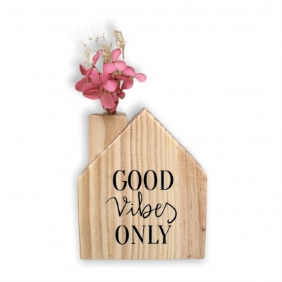 Figura decorativa casa em madeira com texto 'GOOD vibes ONLY' e flores secas cor de rosa.