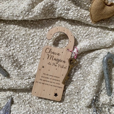 Gancho decorativo de madeira com texto sobre fundo têxtil e enfeites natalícios