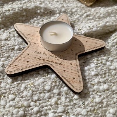 Vela branca numa base em madeira em forma de estrela com texto gravado