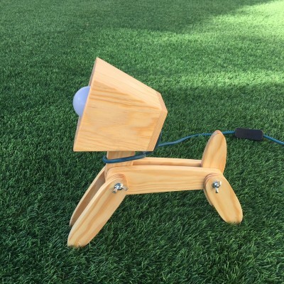 Candeeiro de mesa de madeira em forma de cão sobre relva artificial verde