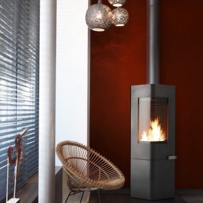 Lareira moderna preta com cadeira de vime e candeeiros pendentes numa sala com parede vermelha