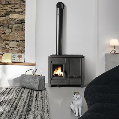 Fogão a lenha preto com chama, saco de feltro e gato sentado no chão junto a sofá preto