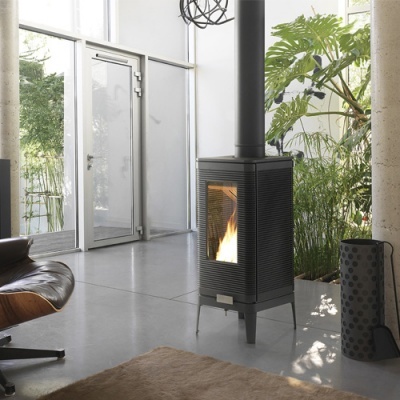 Lareira preta metálica com chama visível num ambiente moderno com poltrona e plantas