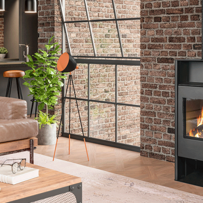 Sala com parede de tijolos, lareira preta a lenha, sofá bege e mesa de madeira clara