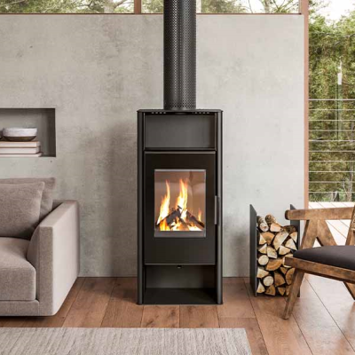 Estufa de metal preto acesa entre sofá cinza e cadeira de madeira com vista para varanda