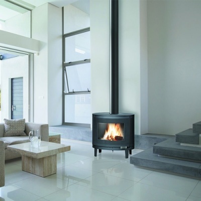 Lareira estufa preta cilíndrica com fogo num interior moderno