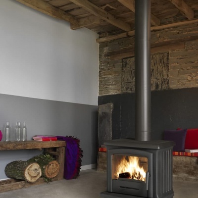 Lareira a lenha preta em sala com teto de madeira e banco com almofadas