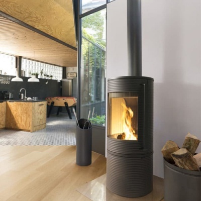 Lareira metálica preta com fogo numa sala moderna com utensílios e lenha