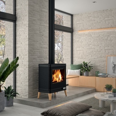 Lareira a lenha preta com pernas de madeira em sala moderna com paredes brancas e plantas