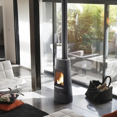 Lareira moderna preta em sala com cadeirão branco e chão cinzento junto a parede de vidro