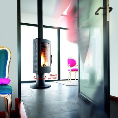 Lareira preta cilíndrica com cadeira antiga estofada e porta de vidro