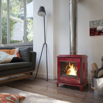 Lareira vermelha com fogo numa sala com sofá e candeeiro