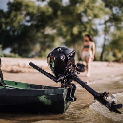Caiaque verde com motor de popa na água junto à praia