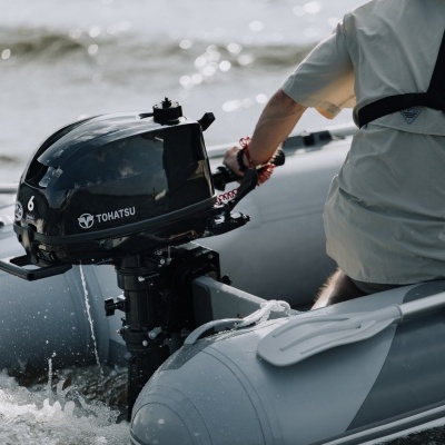 Motor de popa Tohatsu 6 HP em barco insuflável cinza claro com pessoa a conduzir