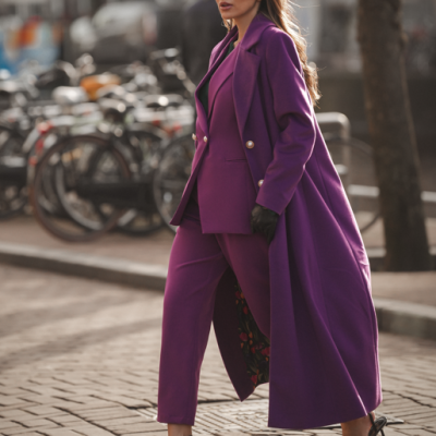 Mulher com conjunto roxo elegante e óculos escuros a andar numa rua com bicicletas ao fundo