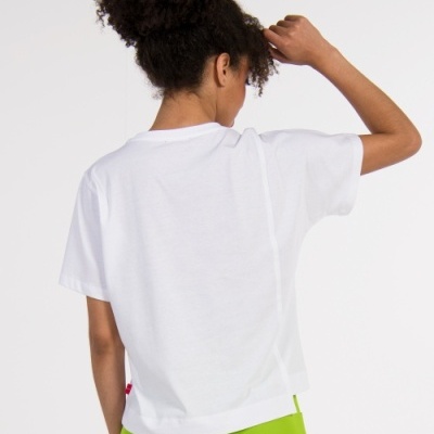 Pessoa de costas a usar camiseta branca de manga curta e calças verdes