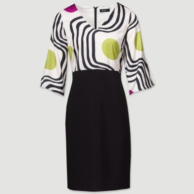Vestido com part superior estampada em branco com padrões ondulados pretos e círculos verdes e roxos, mangas 3/4 e parte inferior preta.