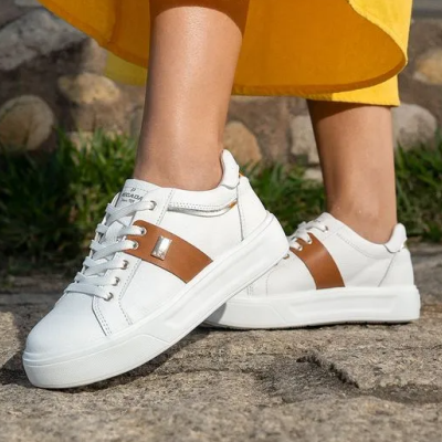 Ténis brancos com detalhes castanhos em cenário exterior