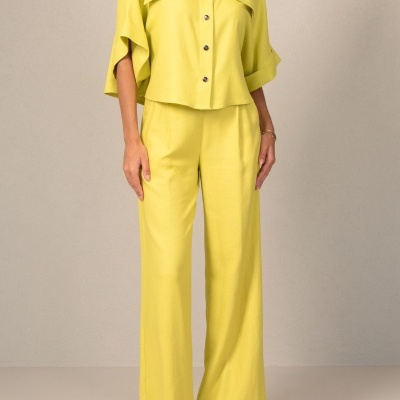 Conjunto feminino amarelo com camisa de botões e calças largas em fundo neutro