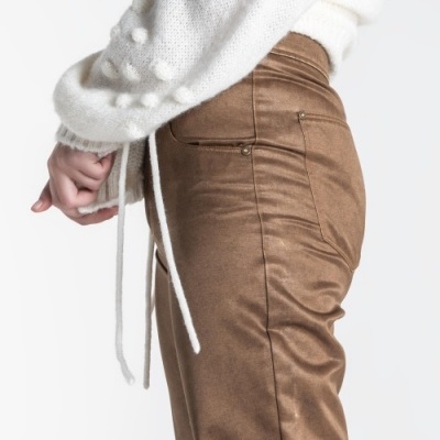 Calças castanhas de tecido e camisola branca de malha com pompons