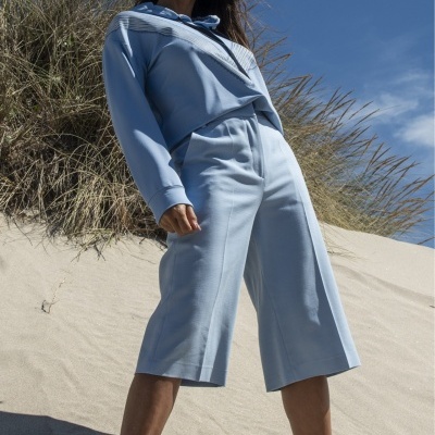 Mulher com roupa azul claro e óculos escuros na praia