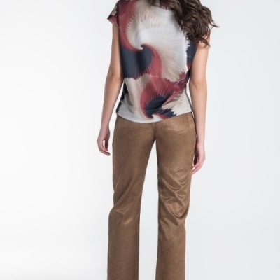 Mulher de costas com t-shirt colorida, calças castanhas e sapatilhas castanhas num fundo branco