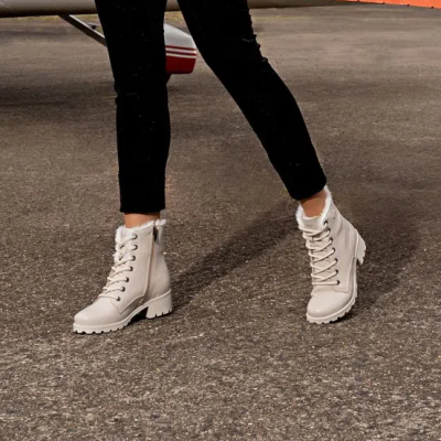 Botas bege claro com atacadores brancos e zíper lateral, usadas em estrada