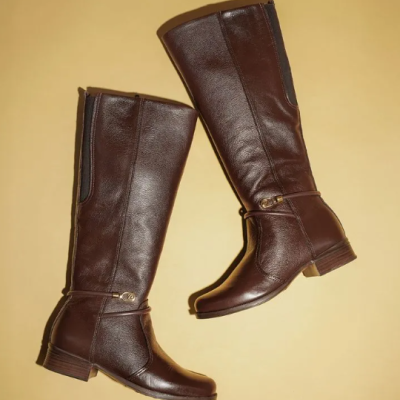 Botas castanhas altas de couro com fivela dourada em fundo amarelo