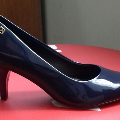 Sapato de salto alto verniz azul escuro com detalhe metálico, em superfície vermelha